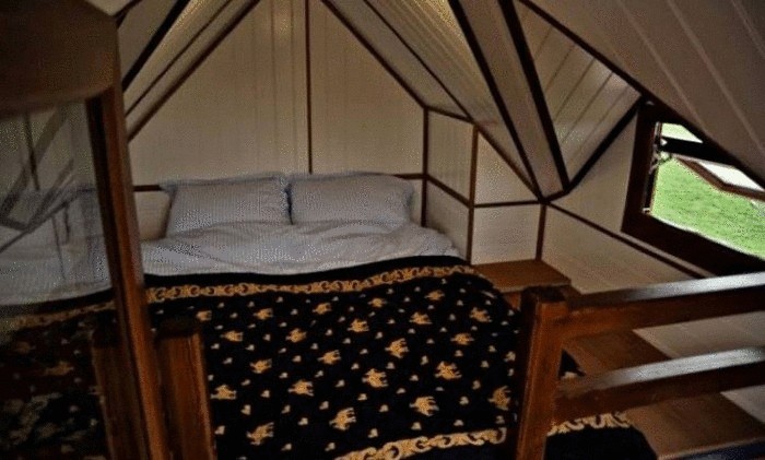 Большая кровать, установленная в крошечном домике.